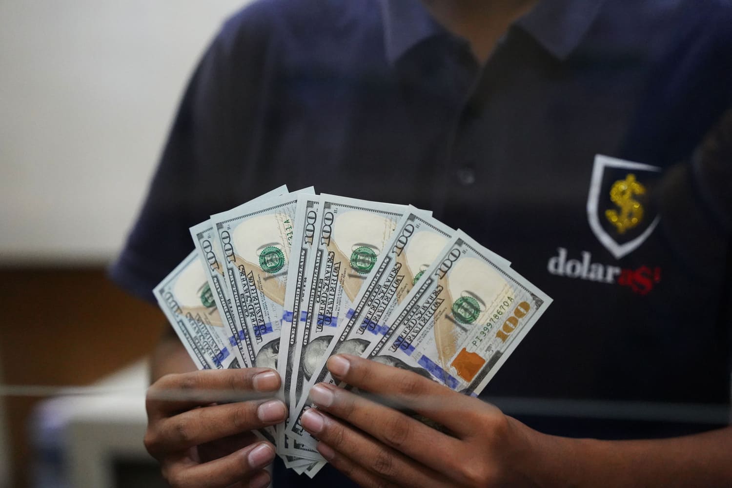 Petugas menunjukkan uang Dolar AS di Money Changer Dolarasia