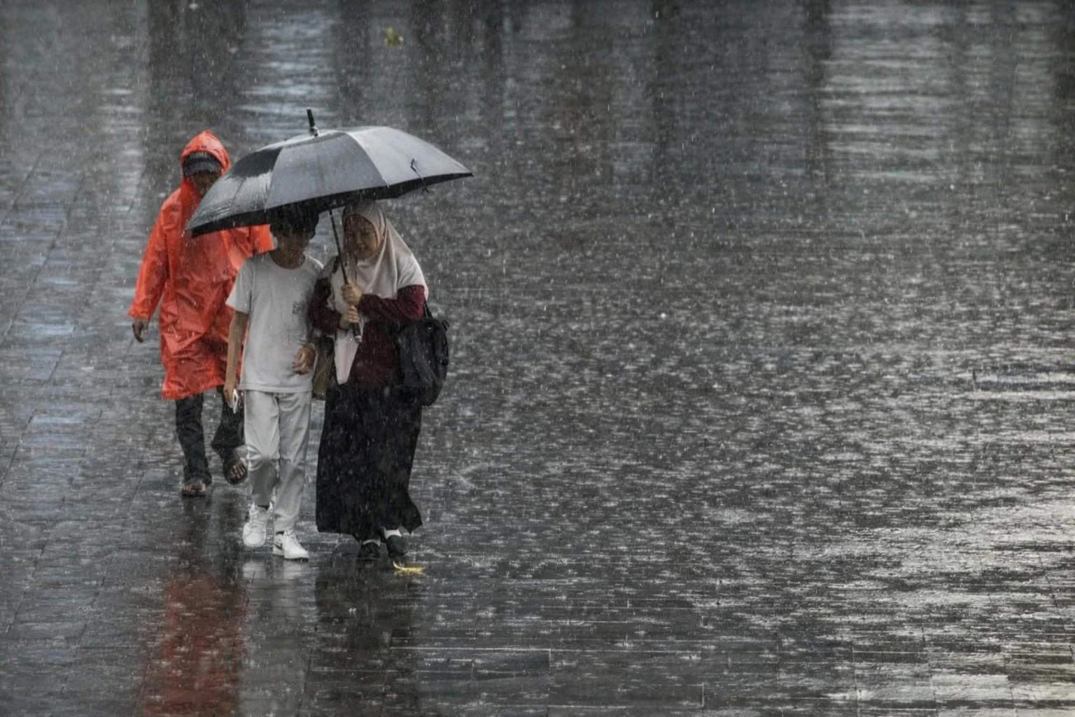 warga menggunakan payung saat hujan deras